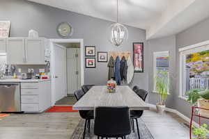 Dining room featuring light wood-style flooring, vaulted ceiling, and a chandelier
