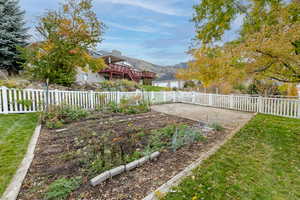 Fenced backyard featuring a mountain view and a vegetable garden