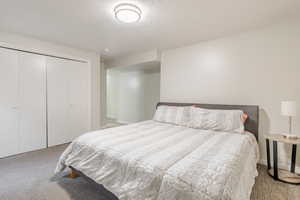 Bedroom featuring light carpet, a textured ceiling, and a closet