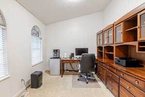Home office with light colored carpet and vaulted ceiling