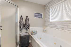 Full bathroom featuring a tub with jets, a shower stall, and wood walls