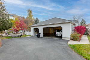View of side of property with stucco siding, roof with shingles, and asphalt driveway