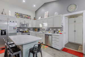 Kitchen featuring appliances with stainless steel finishes, a breakfast bar area, light wood-type flooring, a center island, and white cabinetry