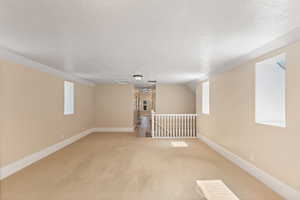 Carpeted empty room with a textured ceiling and baseboards