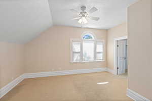 Bonus room featuring light colored carpet, ceiling fan, and lofted ceiling