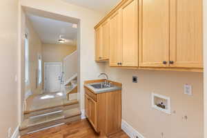 Laundry room with cabinet space, light wood-style floors, hookup for a washing machine, and electric dryer hookup