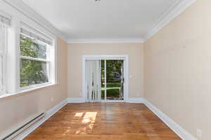 Spare room featuring baseboard heating, crown molding, and wood finished floors