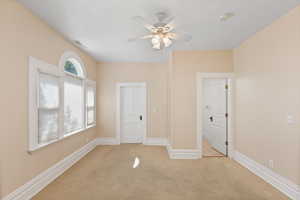 Unfurnished room with light colored carpet and a ceiling fan