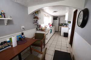 Kitchen featuring wainscoting, a textured wall, a textured ceiling, light countertops, and open shelves