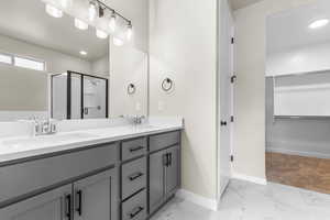 Bathroom with a walk in closet, double vanity, light marble finish floors, a shower stall, and recessed lighting