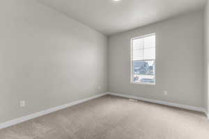 Carpeted spare room featuring baseboards
