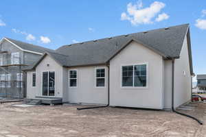 Rear view of property with a shingled roof, stucco siding, and entry steps