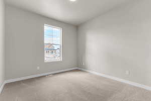 Empty room with light colored carpet and baseboards