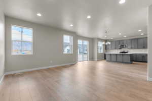 Unfurnished living room with a chandelier, recessed lighting, light wood finished floors, and plenty of natural light