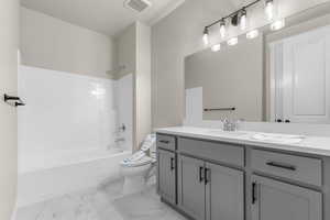 Full bath with bathtub / shower combination, vanity, and light marble finish flooring