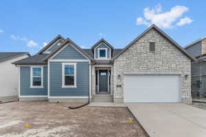View of front of home with driveway, a garage, and stone siding