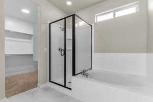 Full bath with a spacious closet, a bath, a shower stall, marble finish flooring, and recessed lighting