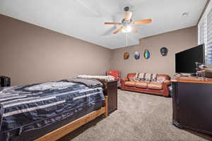 Carpeted bedroom featuring ceiling fan