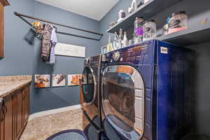 Laundry area with light tile patterned floors, a textured ceiling, and independent washer and dryer