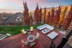 Deck at dusk featuring an outdoor fire pit, a fenced backyard, and a mountain view