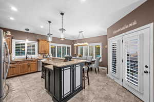 Kitchen featuring a breakfast bar, light stone countertops, dark cabinetry, pendant lighting, and brown cabinetry