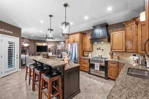 Kitchen featuring arched walkways, a breakfast bar area, a fireplace, light stone countertops, and pendant lighting