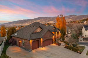 View of front of property with brick siding, driveway, roof with shingles, and a mountain view