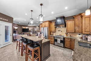 Kitchen with arched walkways, a ceiling fan, a breakfast bar area, a center island, and light stone countertops