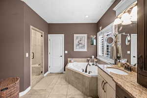 Primary Bathroom featuring a garden tub, vanity, light tile patterned flooring, and a stall shower