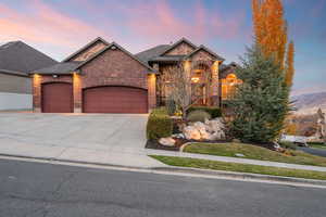 View of front of property featuring an attached garage, driveway, brick siding, and roof with shingles
