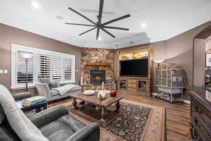 Living area with wood finished floors, a fireplace, arched walkways, ceiling fan, and recessed lighting