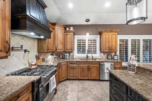 Kitchen featuring tasteful backsplash, brown cabinets, light stone counters, appliances with stainless steel finishes, and recessed lighting