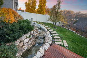 Yard at dusk featuring a fenced backyard and a small water feature pond