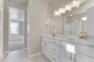 Full bathroom with light tile patterned floors, double vanity, and a stall shower