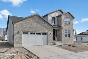 View of front of property with driveway, brick siding, and an attached garage