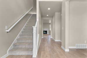 Stairway featuring recessed lighting, a glass covered fireplace, and hardwood / wood-style flooring