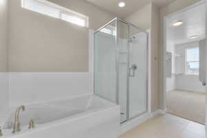 Full bathroom with healthy amount of natural light, light tile patterned floors, a bath, and a stall shower