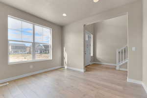 Empty room featuring light wood-style flooring, recessed lighting, stairway, and a textured ceiling