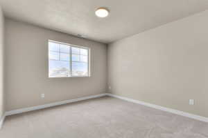 Empty room with light colored carpet and a textured ceiling