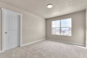 Spare room with a textured ceiling and light carpet