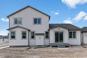 Back of property featuring stucco siding, entry steps, and a shingled roof