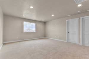 Spare room with light colored carpet, recessed lighting, and a textured ceiling