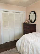Bedroom with dark wood-style flooring, a closet, and crown molding