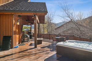 Deck featuring a hot tub, grilling area, and outdoor dining area