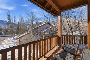 Snow covered deck with a balcony and a mountain view