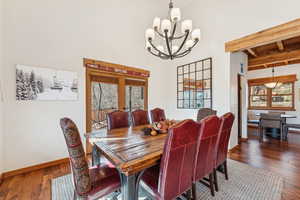 Dining room with beam ceiling, dark wood finished floors, french doors, and a chandelier