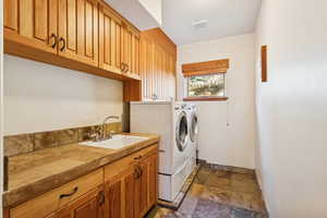 Laundry area featuring stone tile floors, cabinet space, and separate washer and dryer