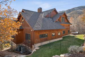 View of home's exterior featuring roof with shingles, a yard, a chimney, and a mountain view