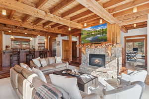 Living area featuring wood finished floors, a stone fireplace, and a wood ceiling with exposed beams