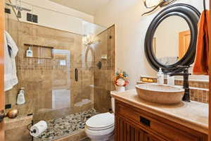 Full bathroom featuring vanity, a shower stall, and a textured wall